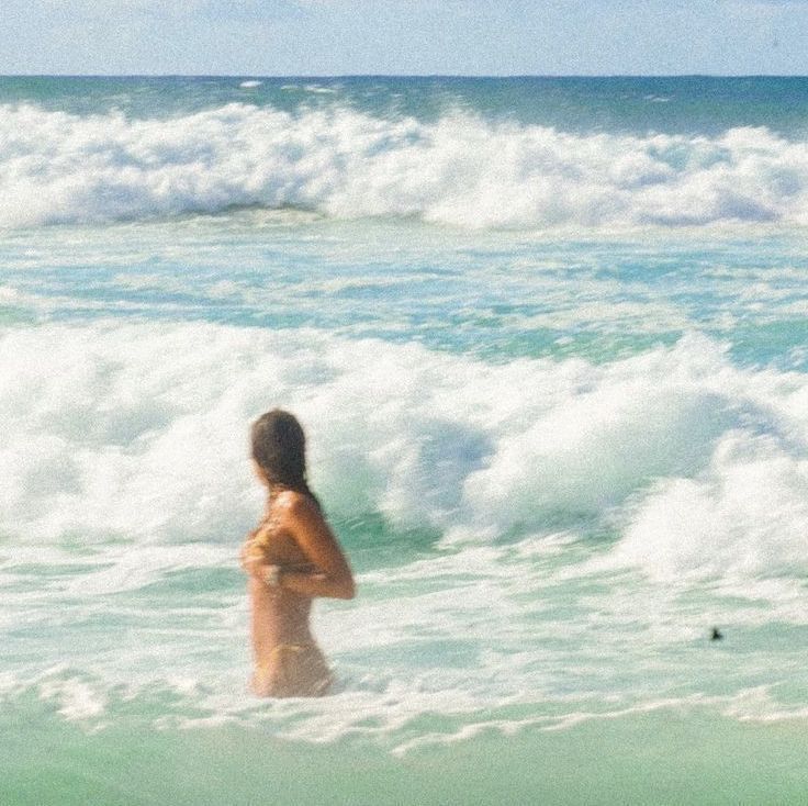 Beach swimmer in turquoise waves, Vesey blog explores sustainable swimwear for ocean adventures.